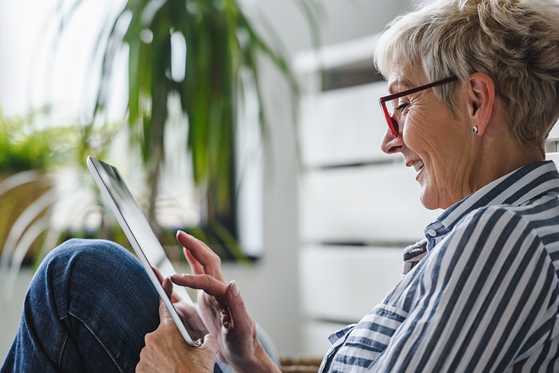 A person wearing glasses reading information on their tablet.